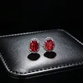 Macro view of elegant oval red gemstone stud earrings featuring a moissanite halo - Earrings (T16) / Red