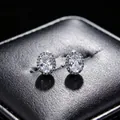 Close-up of sparkling oval moissanite halo stud earrings on black leather display box - Earrings (T16) / White