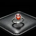 Gros plan d'une bague avec pierre rouge sur un support à bijoux en cuir noir texturé - Bague (T16) / Rouge