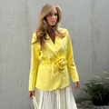 Detailed view of a bright yellow blazer featuring a stylish 3D flower waist decoration - S / Tops / Yellow