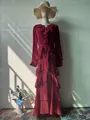 Detailed close-up showing the ruffled layers and elegant brooch of this burgundy maxi dress. - S / Dresses / Red