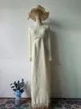 Detail view of an elegant cream maxi dress with pearl neckline and feather trim hemline. - S / Dresses / White