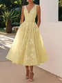 Elegant details of a yellow V-neck floral midi dress featuring a waist tie and A-line skirt. - Yellow