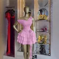 Dettaglio di un elegante abito rosa monospalla a balze con fiore 3D su manichino dorato. - Taglia S / Rosa