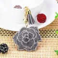 Dettaglio di un portachiavi a forma di rosa con strass e nappa grigia elegante, oro. - Grigio