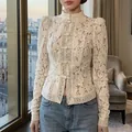 Vue détaillée de l'élégant chemisier en dentelle blanche avec broderies florales. - S / Hauts / Abricot