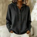 Detailansicht einer dunkelgrauen Strickjacke mit Kapuze, braunen Knöpfen und Rippbündchen - Schwarz