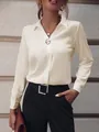 Primer plano de elegante blusa de satén crema con manga larga y broche con estilo - Albaricoque