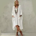 Detail shot of a white lazy-style V-neck linen dress with pockets and irregular hemline. - White