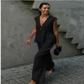 Full view of a woman wearing a black sleeveless V-neck top and wide-leg trousers set outdoors - S / Top And Bottom / Black