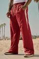 Red men's loose casual trousers with white side stripe shown in a sunny beach setting - S / Bottoms / Red