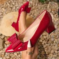 Detailed view of red crocodile textured block heel pumps featuring an elegant bow decoration - 36 / Burgundy