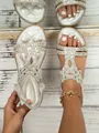 Close-up of silver bohemian flat sandals featuring intricate rhinestone flower patterns. - Silver
