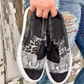 Close-up detail of stylish mixed leopard and snakeskin print patches on denim canvas slip-ons. - 36 / Black