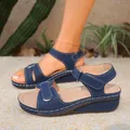 Close-up of blue retro wedge sandals with adjustable hook and loop straps on sand - Blue