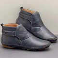 Close-up detail of navy blue leather flat ankle boots with velcro strap and stitching - 35 / Blue