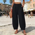 Close-up detail of women's loose black harem pants in a sunny European square setting - S / Bottoms / Black