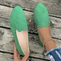 Eleganti mocassini da donna in pelle scamosciata verde a punta tonda su fondo di legno rustico - Verde