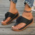 Detail of black wedge thong sandals with 3D flower decoration on wooden background - Black
