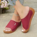 Close-up of red wedge open-toe slippers featuring stylish white contrast stitching - Burgundy