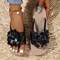 Detailweergave van zwarte platformsandalen met bloemdecoratie en gevlochten zool - Zwart