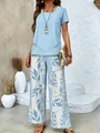 Inquadratura intera di una donna con top blu e pantaloni a gamba larga con foglie. - Taglia S / Top E Pantaloni / Celeste