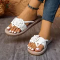 Vue détaillée de tongs blanches élégantes à fleurs et brides tressées portées par un modèle. - 36 / Blanc