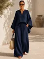 Ensemble élégant haut à col en V bleu marine et pantalon large dans un cadre extérieur. - Bleu marine