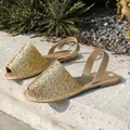 Detail view of sparkling gold glitter flat sandals on a stone surface - 36 / Gold