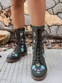Detailed view of dark green mid-calf boots with colorful floral embroidery on a model - Green