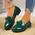 Close-up detail of dark green patent leather loafers with bow accent and thick black lug sole - Green Bow