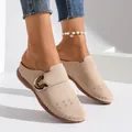 Close-up of beige closed-toe mules featuring laser-cut patterns and a metal buckle detail. - 36 / Off White
