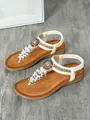Detailed view of Bohemian flat sandals with colorful beads and white fringe tassels. - White