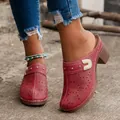 Close-up of red vintage carved chunky heel mules with floral patterns and studs. - 36 / Red