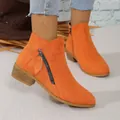 Close-up of bright orange suede ankle boots with stylish side zipper and low heel. - Orange Red