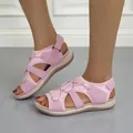 Detailweergave van roze platte damessandalen met klittenbandsluiting aan de voeten. - 38 / Roze