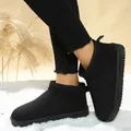 Close-up of black suede slip-on snow boots for women worn on a white fluffy rug in winter - 36 / Black