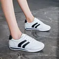 Detail shot of white lace-up leather sneakers with black stripes on model's feet. - 35 / White & Black 309