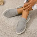 Detailed view of women's grey suede flat loafers with white soles on a woven rug. - 35 / Light Gray