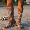 Detailed view of brown embroidered cowboy boots with square heel in outdoor setting - 36 / Tan