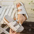 Nahaufnahme von beigen Plateau-Sandalen im Birkenstock-Stil mit Metallschnallen und Nieten. - 38 / Gebrochenes Weiß