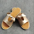 Detailansicht goldener flacher Damen-Pantoletten mit stilvoller Schleife und breiten Riemen - 36 / Gold