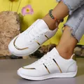 Close-up of stylish white leather sneakers with gold accents worn outdoors by model. - 36 / White