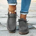 Close-up detail of grey suede loafers featuring white stitching and thick cork-style soles - 36 / Grey