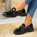Close-up view of elegant black patent leather loafers featuring a decorative gold buckle. - Black Clip