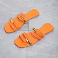 Top view of stylish orange flat sandals with gold metallic accents on a marble floor. - 36 / Orange Red