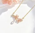 Dettaglio ravvicinato della collana di fiori di ciliegio con ciondolo a goccia brillante - Gold Double Cherry Blossom
