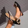 Primer plano de sandalias planas negras de punta con hebillas doradas decorativas. - 36 / Negro