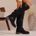 Close-up detail of black slouchy suede boots featuring stylish round metal buckle straps. - 35 / Black
