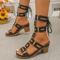 Detail view of black lace-up gladiator sandals with gold hardware on a model. - 36 / Black